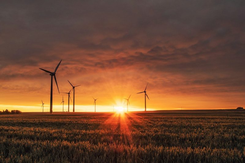 Wind turbines at sunset in an open field